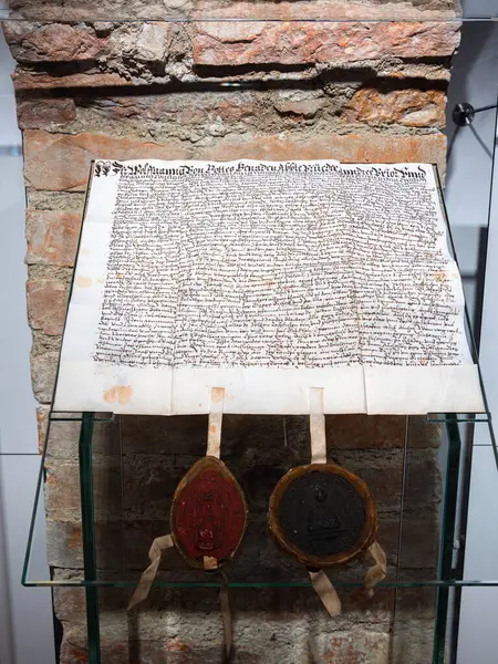 Michaelbeuern, Avusturya - 22 Ekim 2024: Tuğla bir duvara karşı cam bir kutuda sergilenen antik bir el yazısı ve altta iki büyük balmumu mühür.