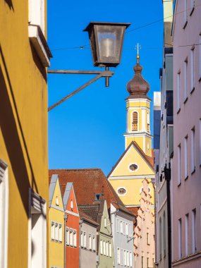 Sarı kilisesi ve sokak lambası olan ortaçağ Landshut 'ının tarihi eski kasaba evleri. Bavyera, Almanya.