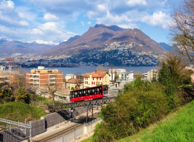 Lugano, İsviçre - 26 Mart 2025: Önünde füniküler demiryolu San Salvatore, arkasında dağlar ve gölle Lugano şehrinin manzaralı manzarası.