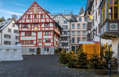 Sankt Gallen, İsviçre - 1 Ocak 2025: Noel ışıkları ve küçük Noel ağaçlarıyla süslenmiş geleneksel yarı ahşap binalarla dolu pitoresk kasaba meydanı.
