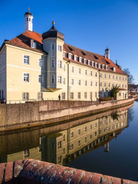 Landshut, Almanya - 19 Mart 2025: Landshut 'ta Isar Nehri' ne yansıyan sarı cepheli tarihi bir bina.