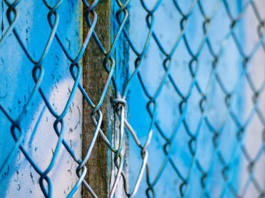 Mavi bir zincire bağlı çitin yakın plan görüntüsü metal bağlantıların dokusunu ve detaylarını ve arkasındaki canlı rengi gözler önüne seriyor..