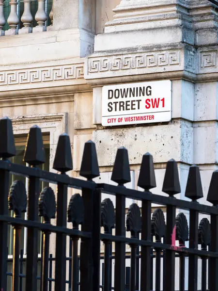 Londra, Birleşik Krallık - 28 Nisan 2025: Westminster 'daki Downing Street SW1 için sokak tabelası, ön planda siyah demir çitlerle kaplı tarihi bir binanın ön cephesinde..