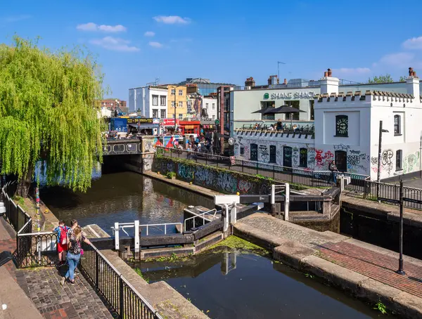 Londra, Birleşik Krallık - 28 Nisan 2025: Bir köprü, grafiti ve yürüyen insanlar ile canlı bir şehir kanalı sahnesi.