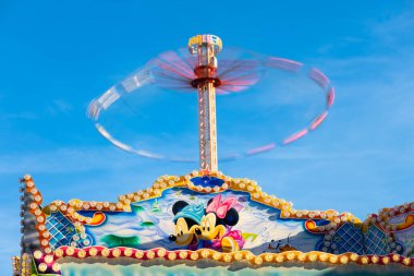 Maastricht, Netherlands - May 12, 2025: A colorful amusement park ride featuring cartoon characters, with a spinning top and bright blue sky in the background.