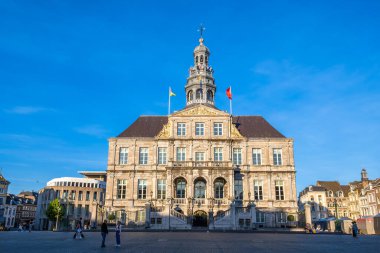 Maastricht, Hollanda - 12 Mayıs 2025: Maastricht 'te tarihi bir belediye binası, arka planda karmaşık mimari detaylar ve açık mavi bir gökyüzü yer alıyor..