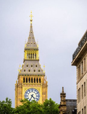 Londra 'daki ikonik saat kulesinin yakın görüntüsü, Big Ben, bulutlu gökyüzüne karşı karmaşık mimarisini ve altın detaylarını gözler önüne seriyor..