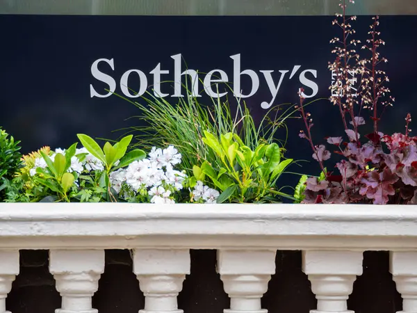 Londra, Birleşik Krallık - 26 Mayıs 2025: Sotheby mağaza vitrinine yakın çekim koyu arkaplan. Aşağıda çeşitli çiçekleri ve yeşillikleri olan dekoratif bir ekici var..