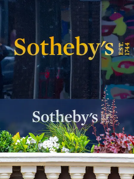 Londra, Birleşik Krallık - 26 Mayıs 2025: Sotheby mağaza vitrinine yakın çekim koyu arkaplan. Aşağıda çeşitli çiçekleri ve yeşillikleri olan dekoratif bir ekici var..