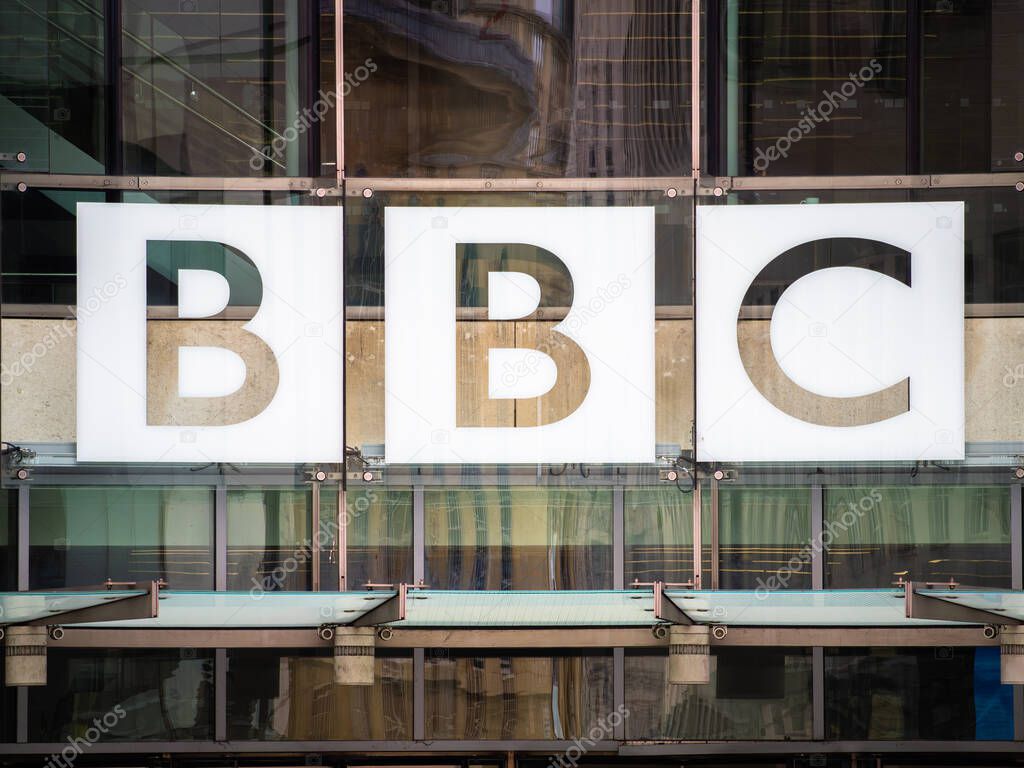 London, United Kingdom - May 26, 2025: Close-up of the BBC logo displayed prominently on a modern glass building facade, showcasing the iconic letters in bold white against a reflective background.