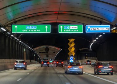 Stockholm, İsveç - 6 Haziran 2025: Stockholm 'de modern bir tünelin içinde çeşitli noktalara giden yolu gösteren ışıklı yol işaretleri olan bir manzara.