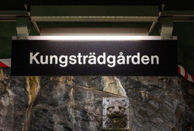 Kungstadgrden adında bir metro istasyonu tabelası. Tabela aydınlandı ve bir taş duvara monte edildi. Altında dekoratif taş bir yüz vardı..