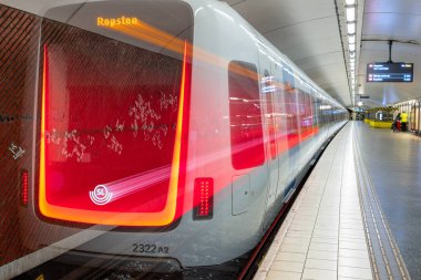 Stockholm, İsveç - 10 Haziran 2025: Stockholm 'de bir metro istasyonunda uzun süre hareketli modern bir trenin teşhir edilmesi, parlak bir tasarım ve aydınlatma tabelaları.