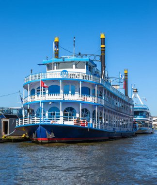 Hamburg, Almanya - 1 Temmuz 2025: Açık mavi bir gökyüzünün altında birden fazla güvertesi olan büyük, renkli bir nehir teknesi. Teknede dekoratif unsurlar ve bayraklar yer alıyor..