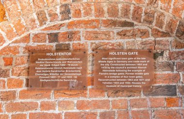 Lubeck, Almanya, 2 Temmuz 2025: Holsten Gate (Holstentor), Avrupa 'nın en ikonik ortaçağ şehir kapılarından biri ve şehrin bir sembolüdür. Almanca ve İngilizce açıklama.