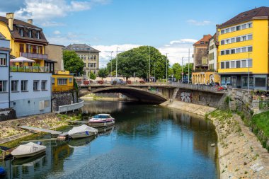 Yverdon les Bains, İsviçre - 24 Temmuz 2025: Sevimli binalarla çevrili, kıyıları boydan boya geçen bir nehir manzarası. Bir köprü nehri geçiyor..