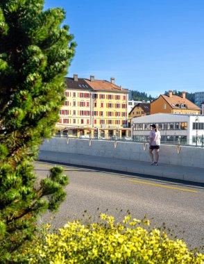 La Chaux-de-Fonds, İsviçre - 19 Eylül 2025: Renkli binalara bakan bir köprüde duran kişi.