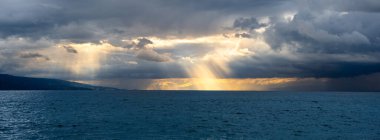 Cenevre Gölü 'nde dramatik bir ufuk. Güneş ışınları kara bulutları delip geçiyor..