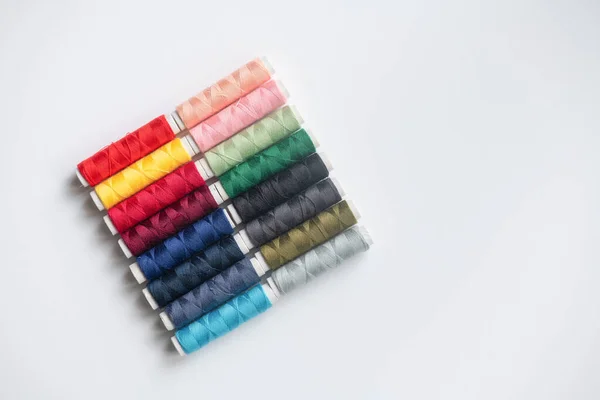 Bobbins of cotton side by side on a white background.