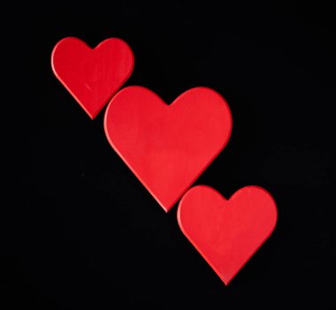 Siyah arkaplanda üç boş kırmızı kalp.