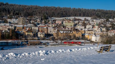 Karlı kış manzarası. Güneşli bir günde Tramelan köyünden geçen kırmızı tren. Bern Canton, İsviçre. Sakin sahne.