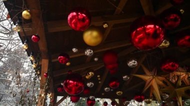Ahşap bir arka planda Noel süsü. Kırmızı ve altın Noel topları ve tahta çatıda asılı yıldızlar. Tatiller.