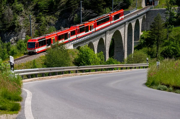 Een Rode Trein Passeert Het Voorjaar Ronde Viaduct Brug Grengiols — Stockfoto