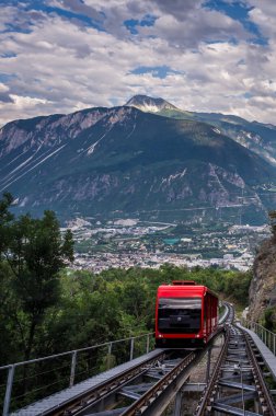 Sierre 'den Crans Montana, Valais Canton, İsviçre' ye kırmızı bir İsviçre füniküleri. Sierre şehri ve dağ manzaralı toplu taşıma aracı..