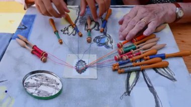 Bobbin danteli yapan eller. Yetişkin, çocuğun zanaat öğrenmesine yardımcı olur. Renkli dantel iplikler. Gerçek zamanlı..