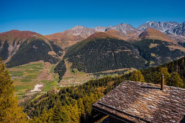 Mountain, chimney and stone tile roof in autumn. Liddes, Valais Canton, Switzerland.