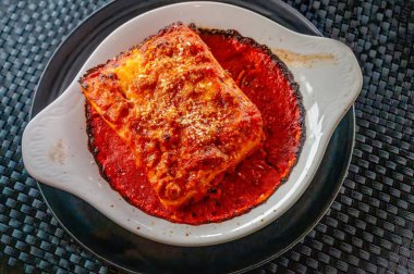 Fırında lazanya, domates sosu ve peynirli beyaz tabak.