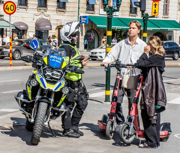 Motosiklet polisi, elektrikli scooterlı çifte Stockholm, İsveç 'te trafikte nasıl davranmaları gerektiğini öğretiyor.