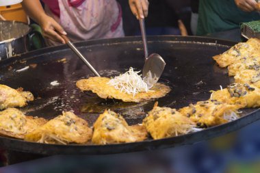 Şef kızarmış istiridye pişiriyor Tayland 'daki en lezzetli sokak yemeği menüsü.