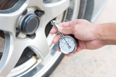  Adam arabayı kullanmadan önce lastik basıncını kontrol etmek için TIRE GAUGE kullanıyor. 
