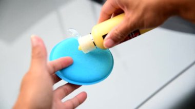 Adam arabayı süngerle silmek ve cilalamak için balmumu döküyor.  