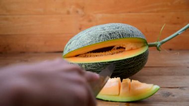 Bıçak kullanan adam portakallı karpuzu ahşap tabakta ikiye böldü.