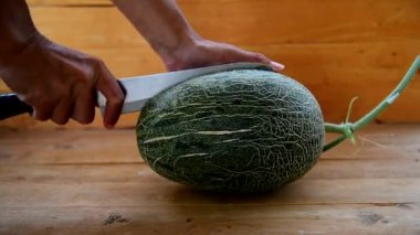 Bıçak kullanan adam portakallı karpuzu ahşap tabakta ikiye böldü.