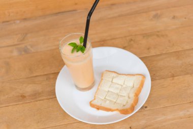 Ahşap tabakta cam içinde süt kavunu Smoothie