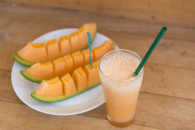 Ahşap tabakta cam içinde süt kavunu Smoothie