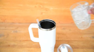 Buz küpünü ahşap masaya Beyaz Handel TumMBler 'a dök  