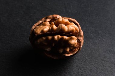 One open walnut on black slate background