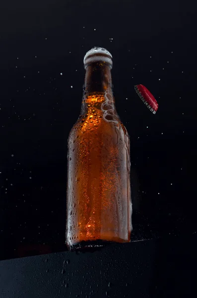 黒を背景に下から見た空気中のキャップと冷たいビールボトル — ストック写真