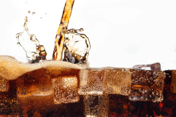 ガラス越しに冷たい氷の上に落ちる爽やかなコーラの飲み物の流れ — ストック写真