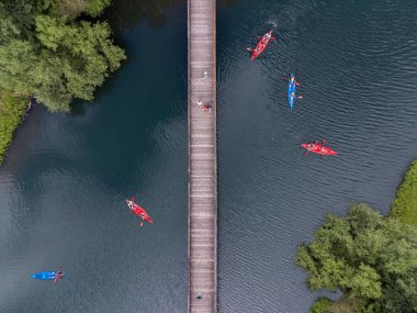 Kanoları olan bir göl manzarası ve yürümek için tahta bir köprü.