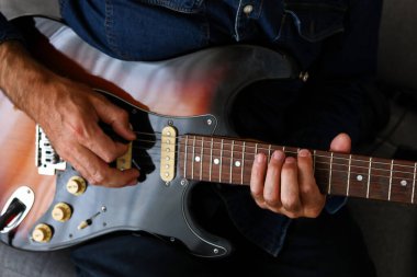 Ön planda elektro gitar dersleri alan bir adam var.