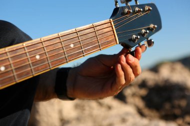Akustik gitar akort eden bir adamın yakın çekimi.