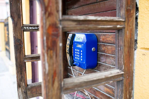 Old wooden telephone booth with blue metal payphone, vintage, retro style
