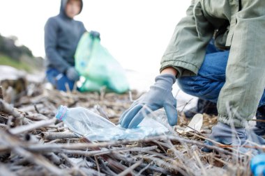 Close-up of a hand cleaning up plastic and garbage outdoors.Environmental protection and ecology