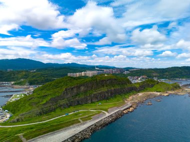 Kaya dağları ve deniz kenarındaki pelerin üzerindeki binalar.