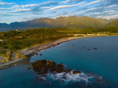 Parlak gün doğumu ışığını denizin üzerindeki uzak sıradağlara yansıtıyor.